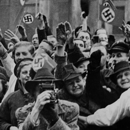 Menschen freuen sich bei der Ankunft von Rudolf Hess. Manche zeigen den Hitlergruß andere schwenken Hakenkreuz-Flaggen.
