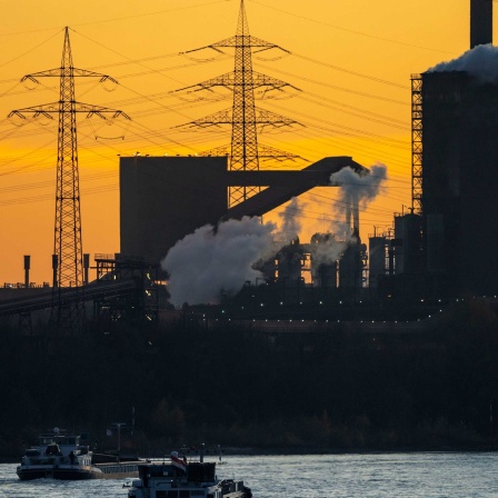 Sonnenuntergang mit Frachtschiffe auf dem Rhein vor Stahlwerk in Duisburg