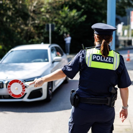 Eine Polizistin stoppt an einer Kontrollstelle an der Grenze ein Fahrzeug.