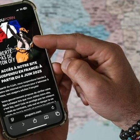 Eine Person hält ein Smartphone in der Hand, auf dem die Seite "Pornhub" geöffnet ist