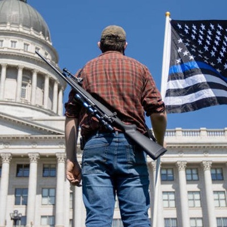 Ein Mann mit einem Gewehr auf dem Rücken vor dem Weißen Haus
