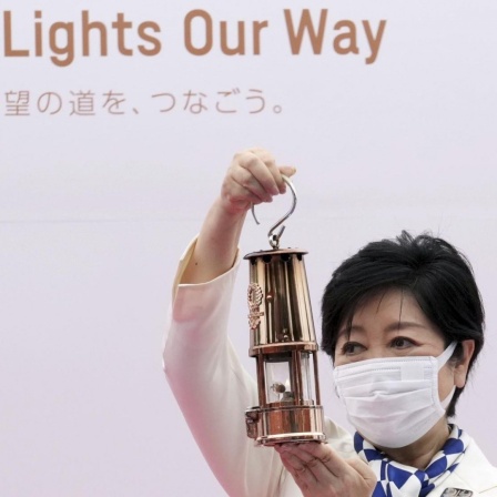 Tokios Gouverneurin Yuriko Koike hält eine Laterne mit der olympischen Flamme in die Höhe.  Die Zeremonie des olympischen Fackellaufs Tokio 2020 fand im Komazawa Olympic Park statt. 