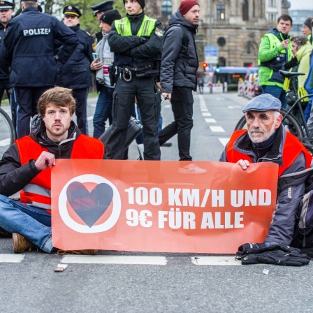 Klima-Aktivisten der &#034;Letzten Generation&#034; haben sich am Karlsplatz in München festgeklebt. Auf einem Transparent steht &#034;100 km/h und 9 € für alle&#034;