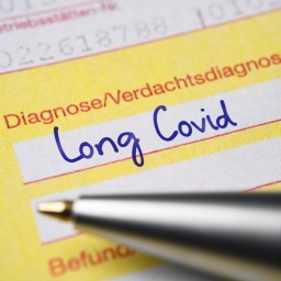 Auf einem ärztlichen Überweisungsschein liegt ein blauer Kugelschreiber, mit dem zuvor die Diagnose Long Covid geschrieben worden ist.