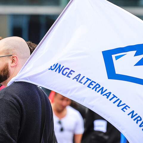 Ein Mitglied der Junge Alternative trägt eine Fahne der Organisation