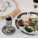 Ein Tisch ist für einen traditionellen Sederabend gedeckt, auf dem Teller liegen etwa Kräter, ein Knochen oder ein Ei.
