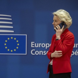 EU-Kommissionspräsidentin Ursula Von der Leyen telefoniert. Im Hintergrund ist das Logo vom Europäischen Rat zu sehen. 