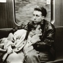 Evelyn Richter "Unterwegs, ohne Jahr". Ein Junges Paar sitzt eng umschlungen in einer Bahn.