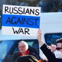 Ein offensichtlich russischer Teilnehmer hält auf einer Demo ein Plakat mit der Aufschrift "Russen gegen Krieg" in Händen