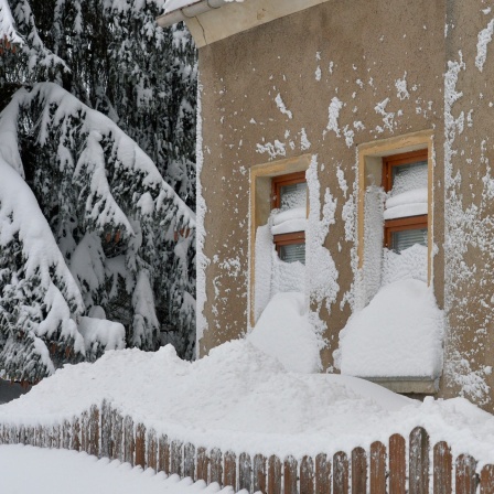 Die Fensterfront eines Hauses ist tief eingeschneit.