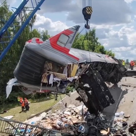 Ein verunglückter Zug hängt an einem Krahn.