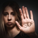 Eine Frau hält ihre Handfläche Richtung Kamera. Darauf steht "Stop".