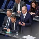 Bundeskanzler Olaf Scholz (SPD, rechts) gemeinsam mit Wirtschafts- und Klimaminister Robert Habeck (Grüne) und Finanzminister Christian Lindner (FDP) auf der Regierungsbank bei der Befragung des Bundeskanzlers. Alle drei tragen dunkle Anzüge, Scholz steht, die beiden Minister sitzen.