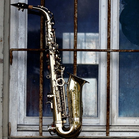 Saxophon vor vergittertem Fenster. 