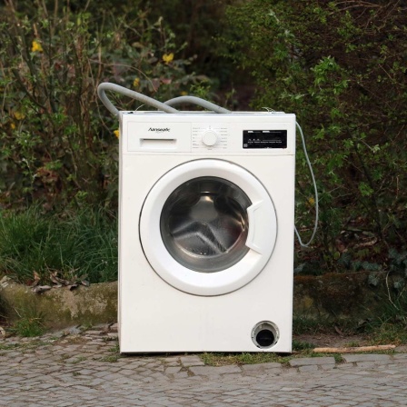 Eine defekte Waschmaschine steht auf einem Gehweg.