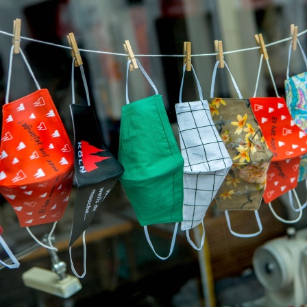 Selbst genähte Masken hängen während der Coronapandemie in einem Schaufenster in Bonn