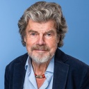 Im Porträt: Bergsteiger Reinhold Messner vor blauem Hintergrund