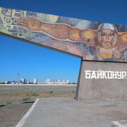 Das Monument "Der Fischer" am Eingang von Baikonur zeigt einen Mann mit ausgebreiteten Armen und Helm, der scheinbar im Weltraum schwebt,