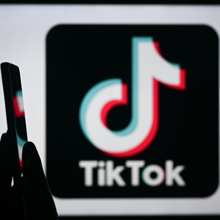 Junge Frau mit Smartphone und TikTok-Logo