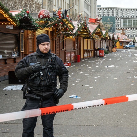 Polizisten stehen vor dem abgesperrten Weihnachtsmarkt in Magdeburg. 