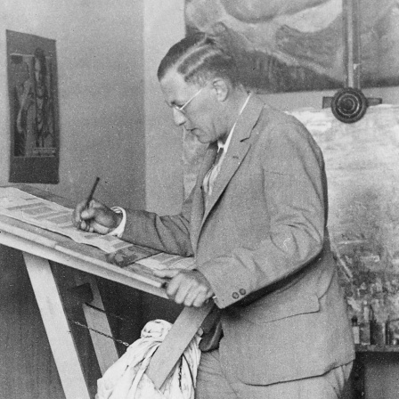 Der Bühnenbildner Caspar Neher steht in seinem Studio und malt. Aufnahme Anfang 1930er Jahre
