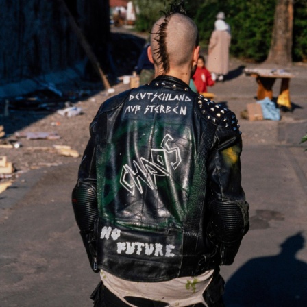 Ein Punker mit Nieten-Lederjacke mit den Aufschriften "Deutschland muß sterben", "No Future" und "Chaos" 