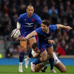 Der französische Rugby-Star Antoine Dupont passt den Ball, während er getackled wird.
