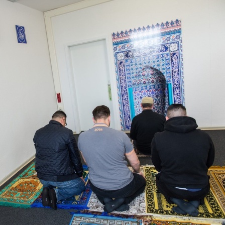 Ein muslimischer Seelsorger betet gemeinsam mit Häftlingen im Gebetsraum in einer Justizvollzugsanstalt.