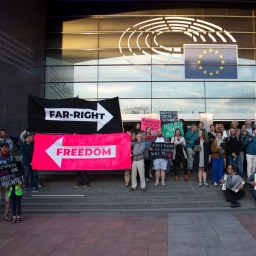 Protest gegen Rechts auf den Stufen des Europäischen Parlaments. Demonstranten halten große Pfeile, die in unterschiedliche Richtungen zeigen und mit "Far-Right" und "Freedom" beschriftet sind.