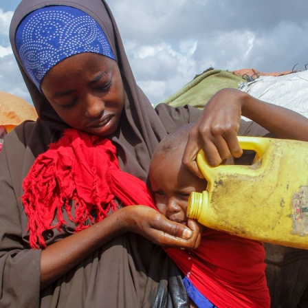 Somalia, Mogadischu: Eine somalische Frau, die aus den von der Dürre betroffenen Gebieten geflohen ist, gibt ihrem Kind Wasser