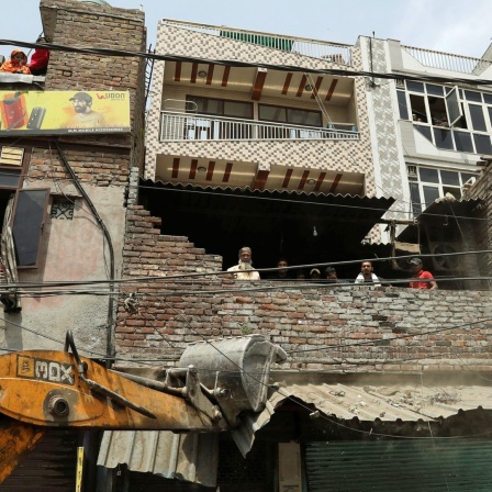 Ein Bulldozer soll ein illegales Haus in Neu-Delhi abreissen.
