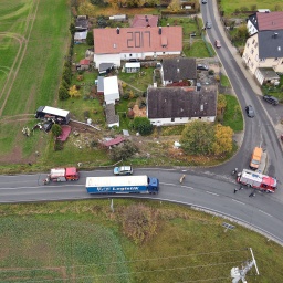 Ein Lkw steht nach einem Unfall auf einem Feld. In einem Graten hinter ihm ist eine Schneise der Verwüstung. Neben dem Lkw steht ein Auto. Es ist nach einem Zusammenprall zerstört. Auf dem Dach des Autos liegt ein Wellblech.