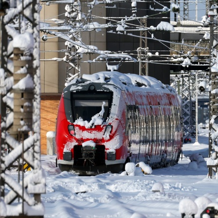 Mit Schnee überzogener Regionalzug steht im Hauptbahnhof München