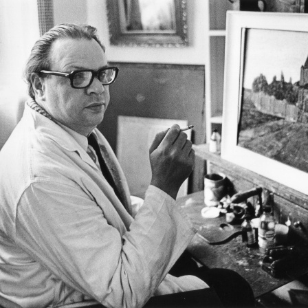 Der Maler Heinz Müller sitzt rauchend vor einem Gemälde.