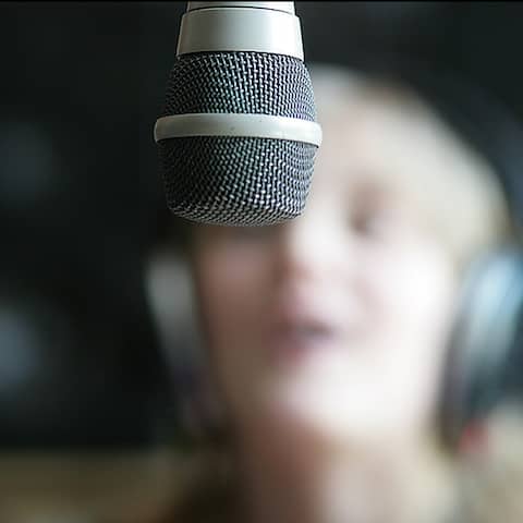 Ein Junges Mädchen hinter einem Mikrofon im Studio.