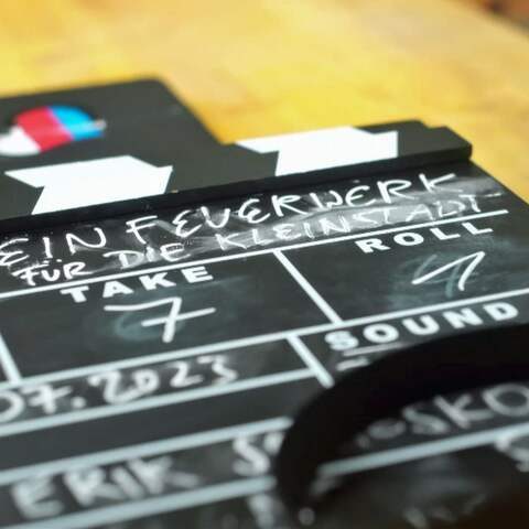Die Filmklappe mit der Aufschrift "in Feuerwerk für die Kleinstadt" liegt auf einem Holztisch (Foto: rbb/Screenshot)