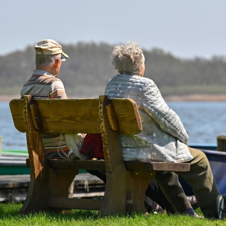 Symbolbild: Ein älteres Paar sitzt auf einer Bank, neben ihnen ein Rollator.