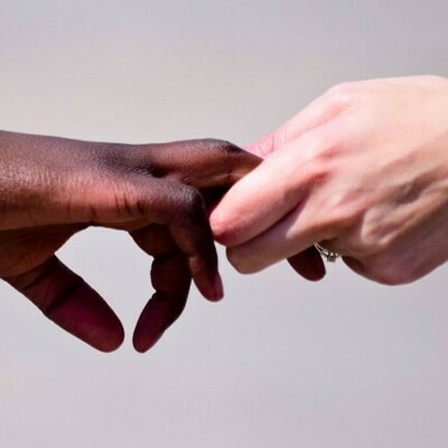 Eine schwarze Frau und ein weißer Mann reichen sich die Hand.
