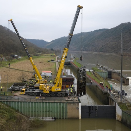 Zwei Kräne heben ein beschädigtes Schleusentor aus der Schleuse Müden. Seit dem 08.12. ist die Schifffahrt auf der Mosel lahmgelegt. Bei einer Kollision eines Frachtschiffs mit der Schleuse ist diese schwer beschädigt worden.