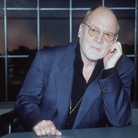 Hanns Dieter Hüsch 1995 aufgenommen, er sitzt an einem Tisch und schaut in die Kamera