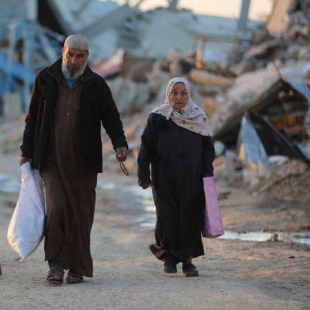 Menschen gehen an zerstörten Gebäuden im Flüchtlingslager Al-Maghazi im Zentrum des Gazastreifens vorbei. Die islamistische Hamas will nach eigenen Angaben die Verhandlungen mit den Vermittlerstaaten fortsetzen, bis eine Vereinbarung über eine Waffenruhe mit Israel erreicht ist.
