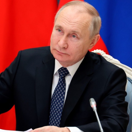 Ein Porträtbild zeigt den Präsident von Russland, Wladimir Putin, an einem Tisch sitzend.