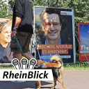 Bilder von Wahlplakaten zur Landtagswahl 2022, im Vordergrund geht ein Mann mit Hund spazieren