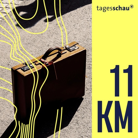Ein Aktenkoffer steht auf dem Boden, während zwei Personen ihren Schatten auf den Boden werfen.