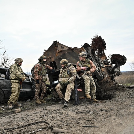Soldaten der Ukraine in der Region Saporischschja stehen vor einem zerstörten Fahrzeug.