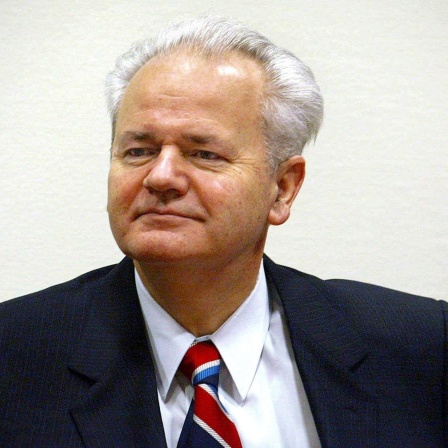 Ein Farbfoto zeigt Slobodan Milošević wird Staatspräsident von Jugoslawien, einen Mann mit Halbglatze, grauem Haar in dunklem Anzug, weißem Hemd und gestreifter Krawatte, sein Blick ist trotzig, selbstbewusst