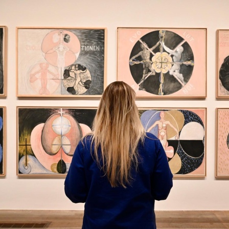 Eine Betrachterin steht vor Gemälden von Hilma af Klint in London.