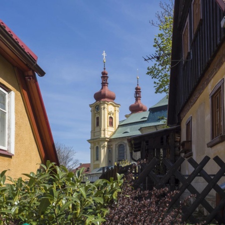 Blick durch Wohnhäuser hindurch auf das Franziskaner-Kloster in Hejnice im Dreiländereck von Tschechien, Polen und Deutschland.