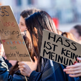 Eine Demonstrantin in Dresden hält ein Schild mit der Aufschrift "Hass ist keine Meinung" hoch.