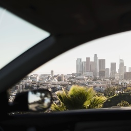 Aussicht aus einem fahrenden Auto mit dem Rückspiegel im Vordergrund.